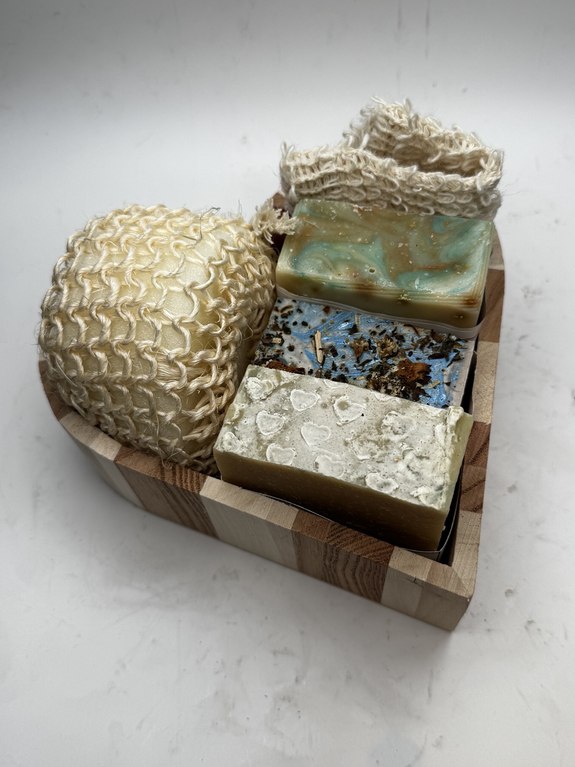 Goat milk soaps and a sisal soap saver in a wooden dish