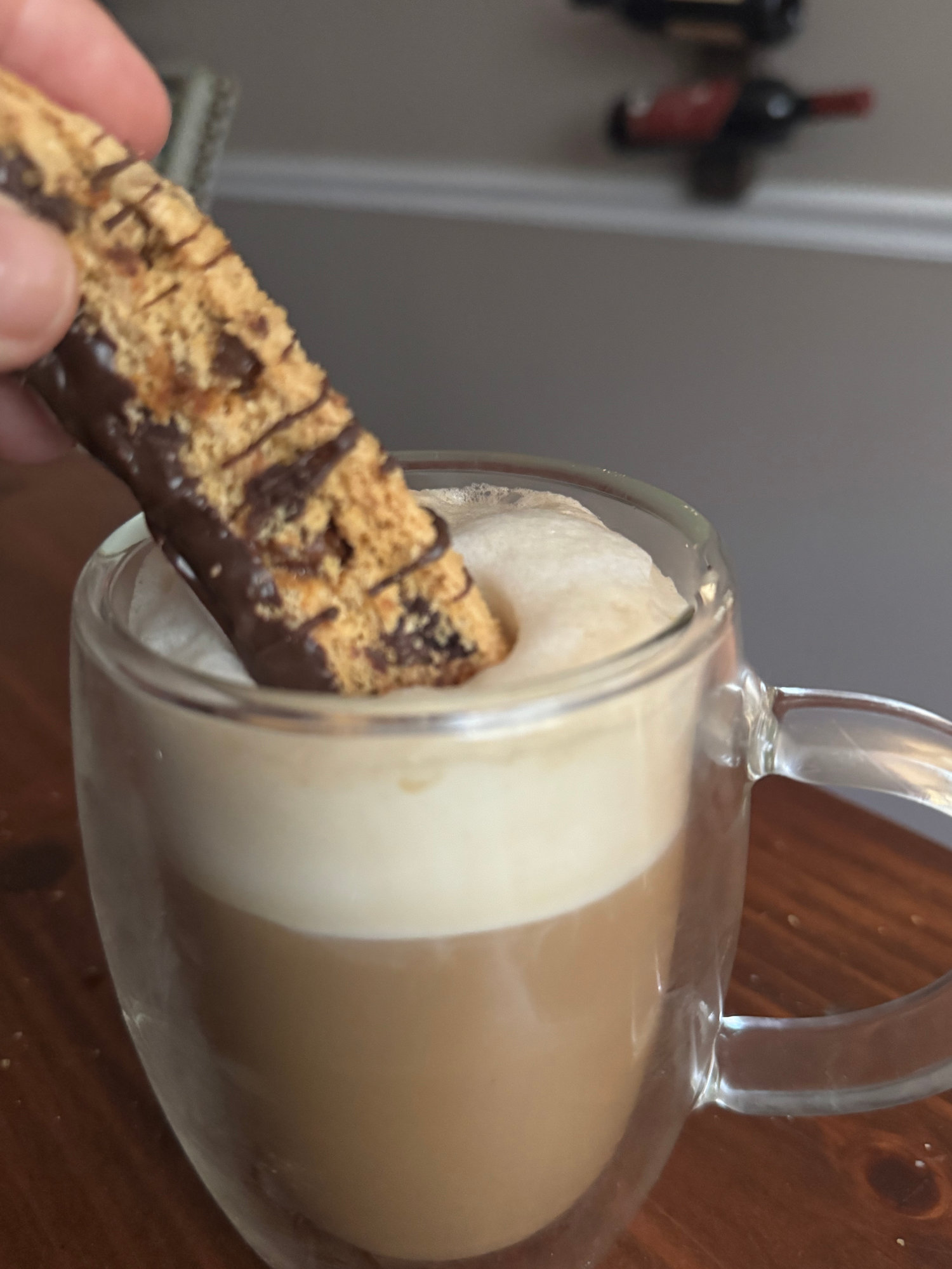 A sourdough biscotti dipped into a frothy coffee